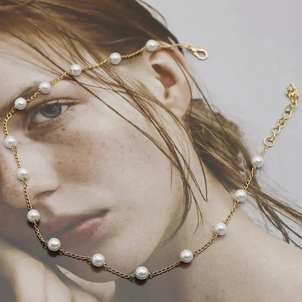 Dainty women's gold choker necklace with lustrous, spaced pearls. Perfect for a delicate and elegant jewelry statement.