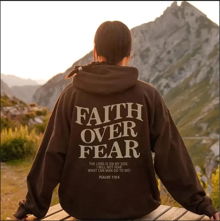 Women's grey "Faith Over Fear" graphic hoodie, close-up of inspirational text.