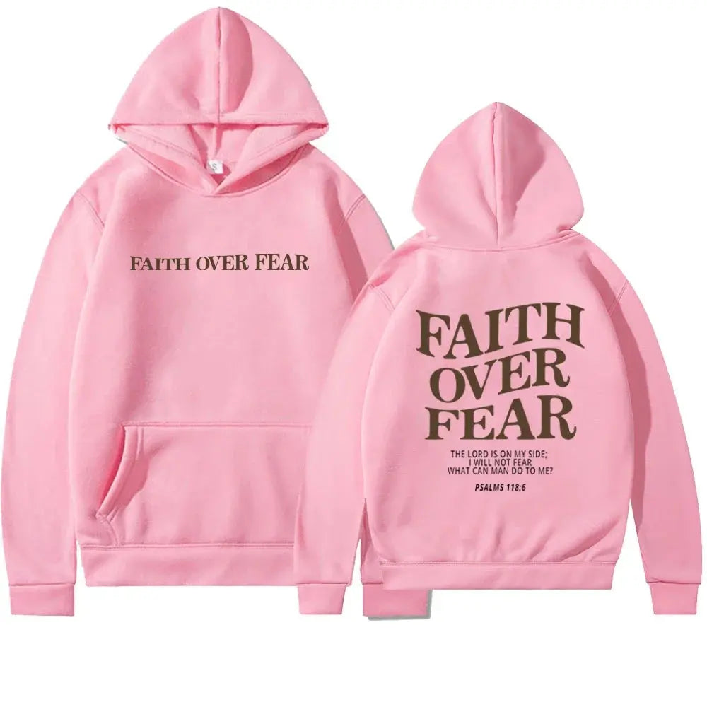 Stylish woman wearing black "Faith Over Fear" pullover hoodie for casual street style.