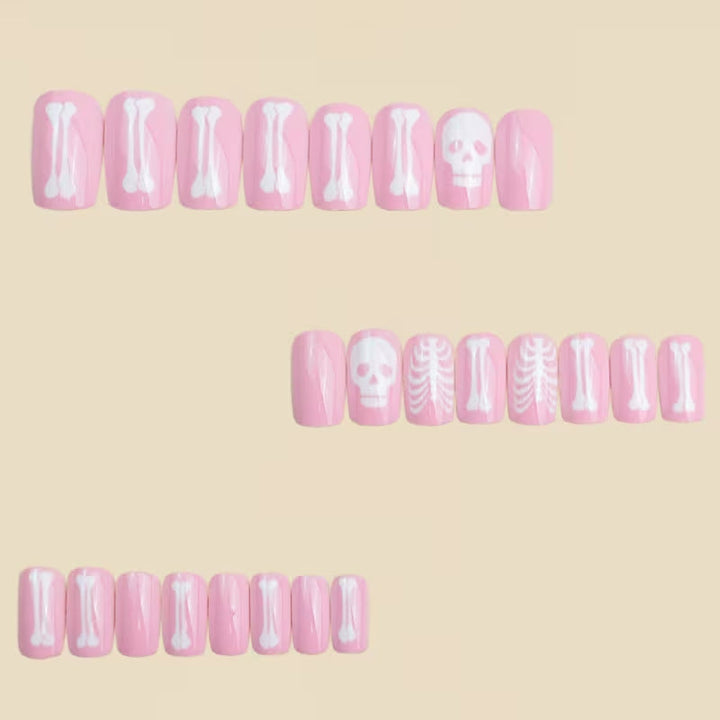 Pale pink Halloween skeleton fake nails for women, with intricate white bone graphics and festive nail art.