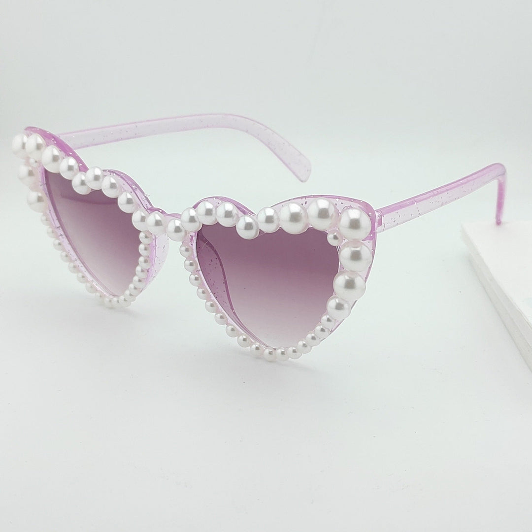 Unique heart-shaped sunglasses with delicate pearl details for women. Trendy summer accessory.