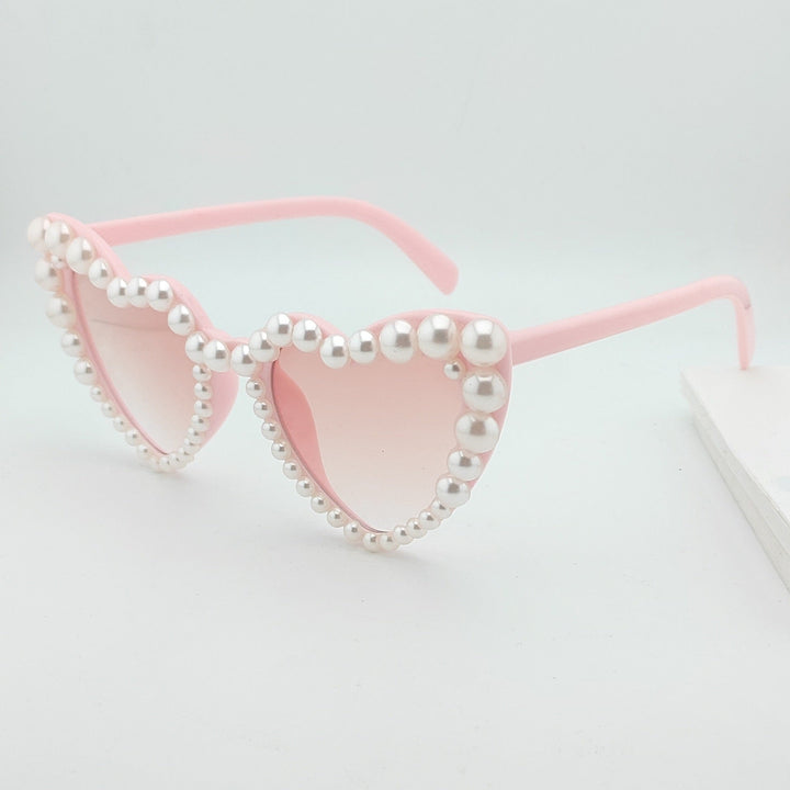 Elegant women's heart-shaped sunglasses with pearls, offering stylish sun protection. Chic accessory.