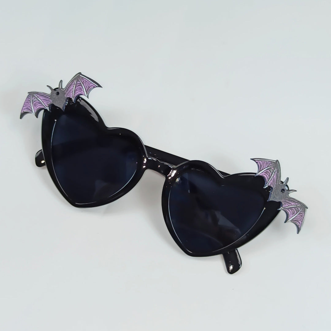 Women's fashion sunglasses: vibrant red heart-shaped frames with playful bat wing accents & UV protection.