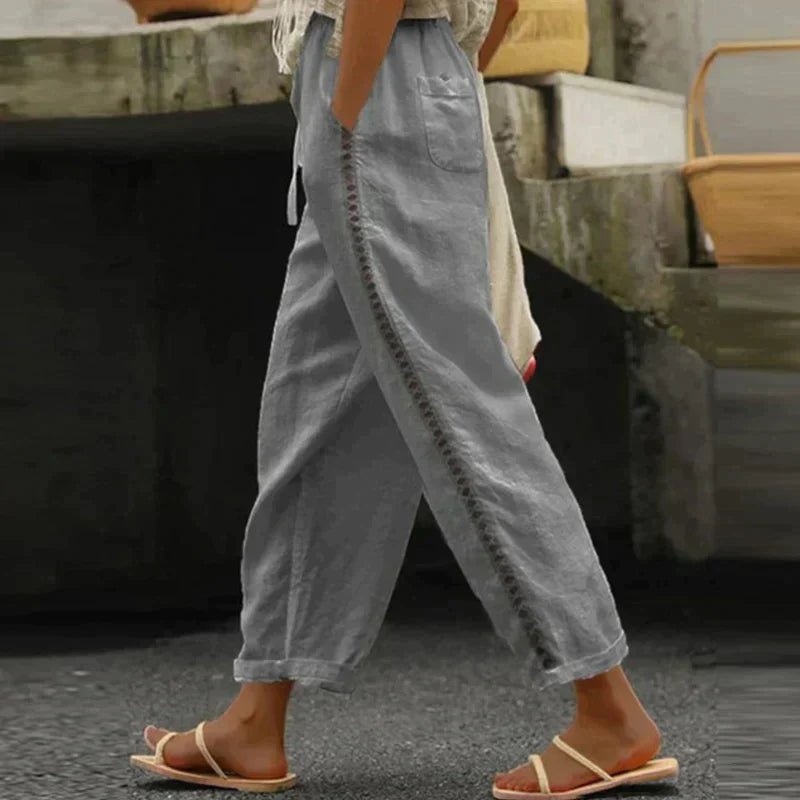 Relaxed fit women's tapered pants, high-waisted with decorative side buttons, ideal for spring & summer style.