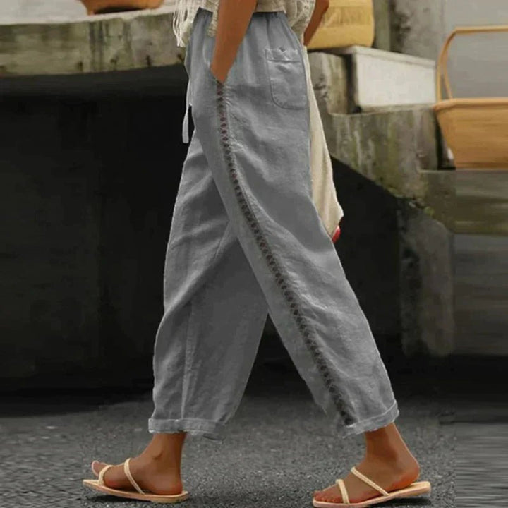 Relaxed fit women's tapered pants, high-waisted with decorative side buttons, ideal for spring & summer style.