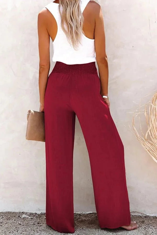 Women's smocked front high-waisted wide-leg trousers, detailed with buttons, ideal for summer style.