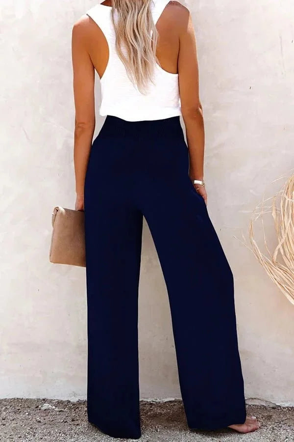 Woman modeling high-waisted wide-leg smocked front trousers, perfect for elegant summer outfits.