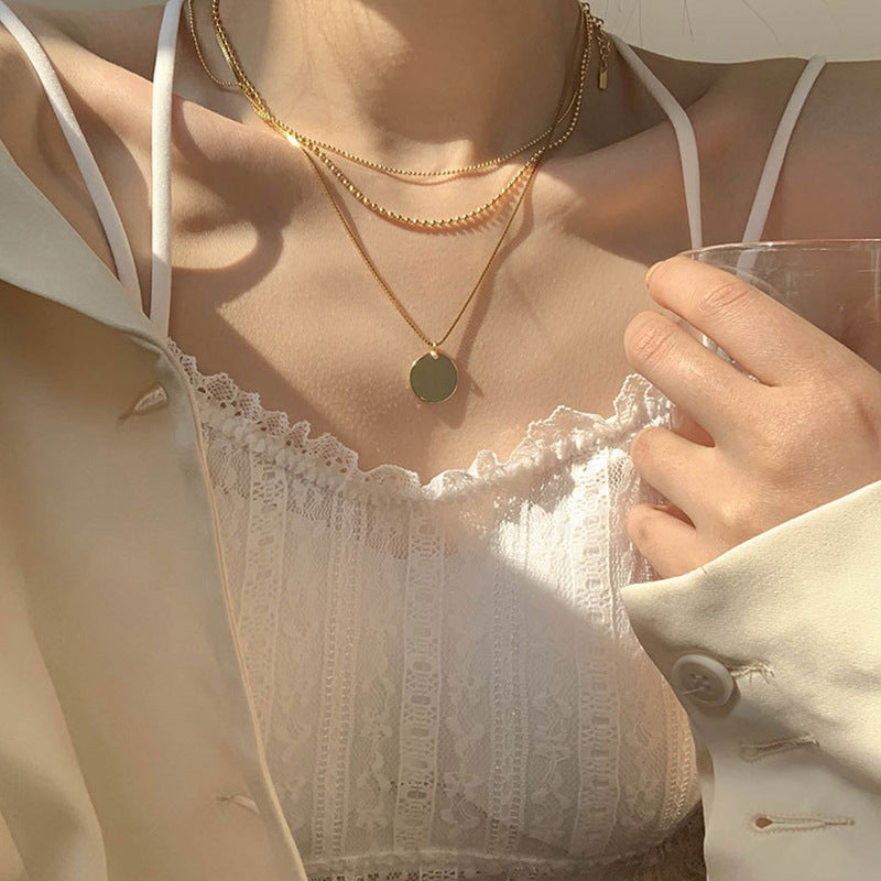 Women's layered dainty pendant necklace with delicate chains & round white pearl-like pendants. Elegant fashion jewelry.