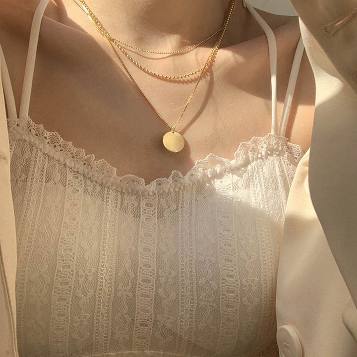 Elegant women's layered dainty necklace featuring multiple delicate chains & subtle round pendants. Perfect fashion accessory.