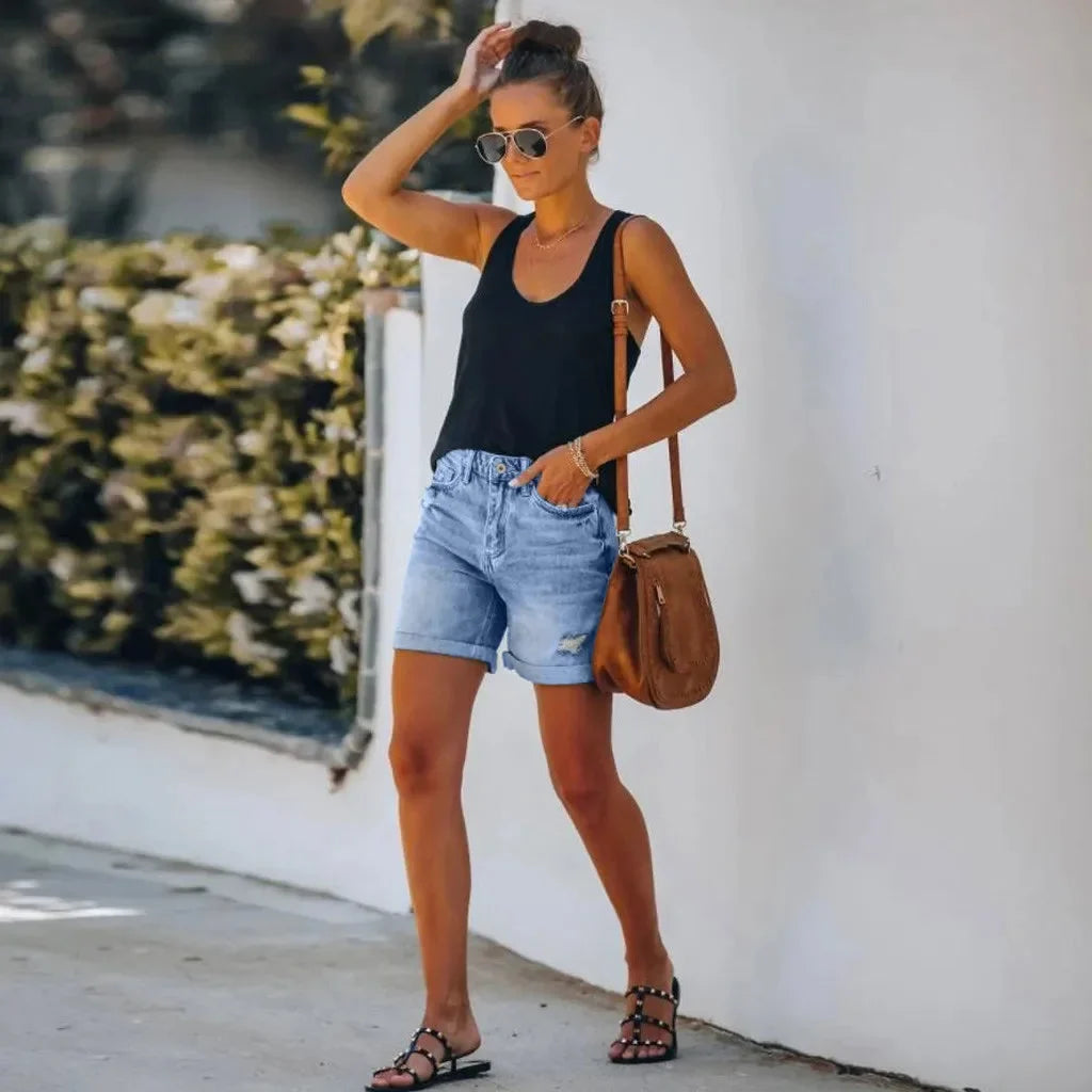 Trendy women's high-waist jean shorts featuring stylish distressing & a rolled hem, ideal for a casual summer look.