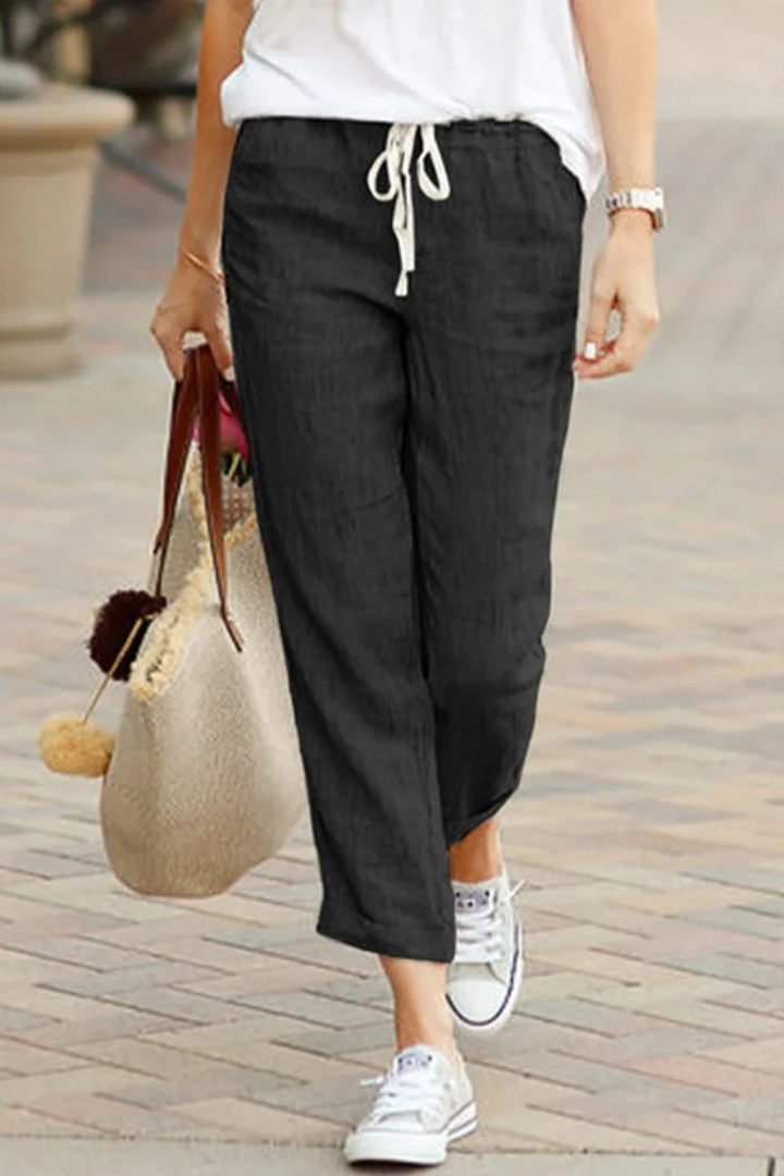 Effortless women's cropped linen trousers with a flexible drawstring waist, great for travel and leisure.