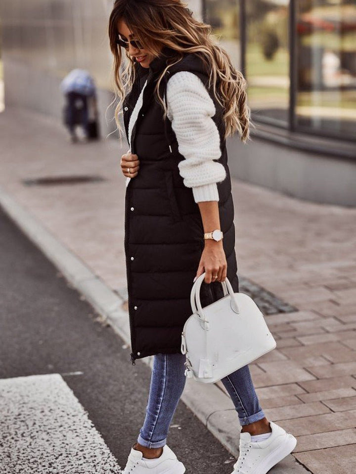 Quilted long puffer vest for women, featuring a cozy hood & practical pockets, perfect for fall/winter.