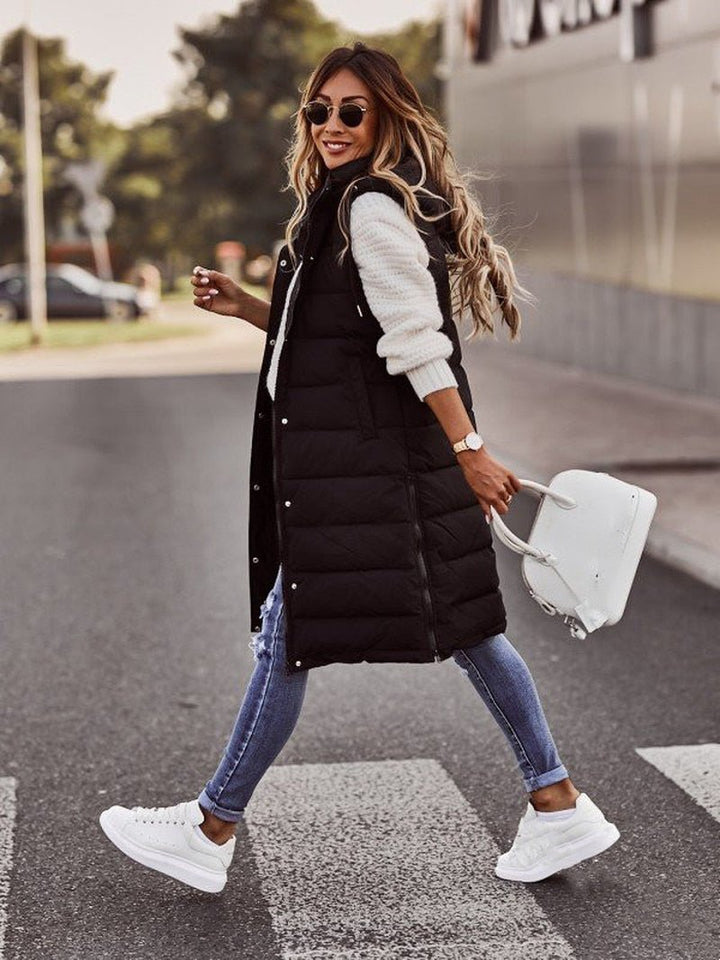 Elegant women's long hooded puffer vest, ideal for stylish layering over sweaters and winter outfits.