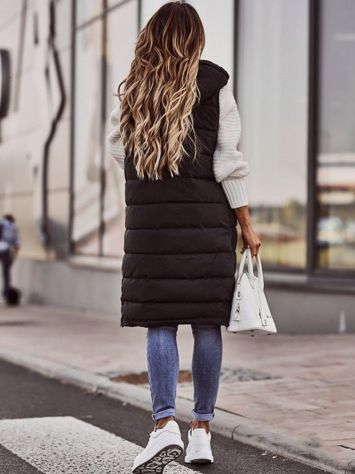 Woman wearing a long black hooded puffer vest, offering warmth and modern style for cold weather.