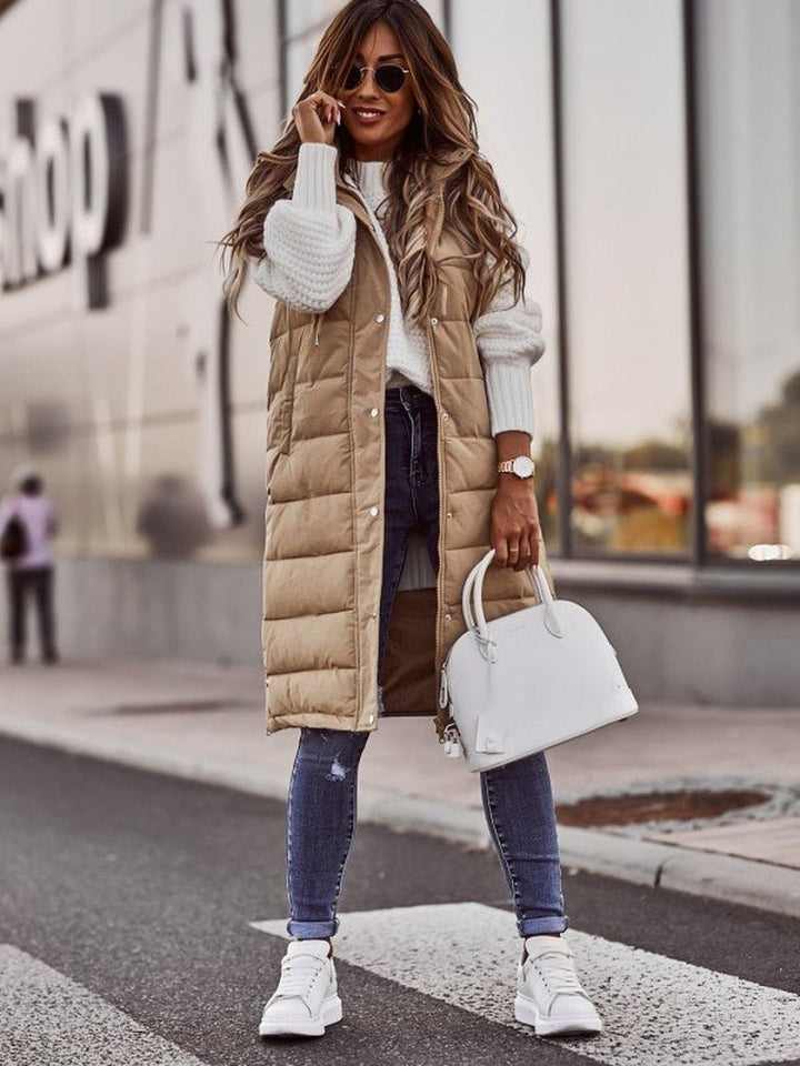 Cozy quilted long puffer vest for women, with a protective hood, ensuring warmth and comfort in outerwear.