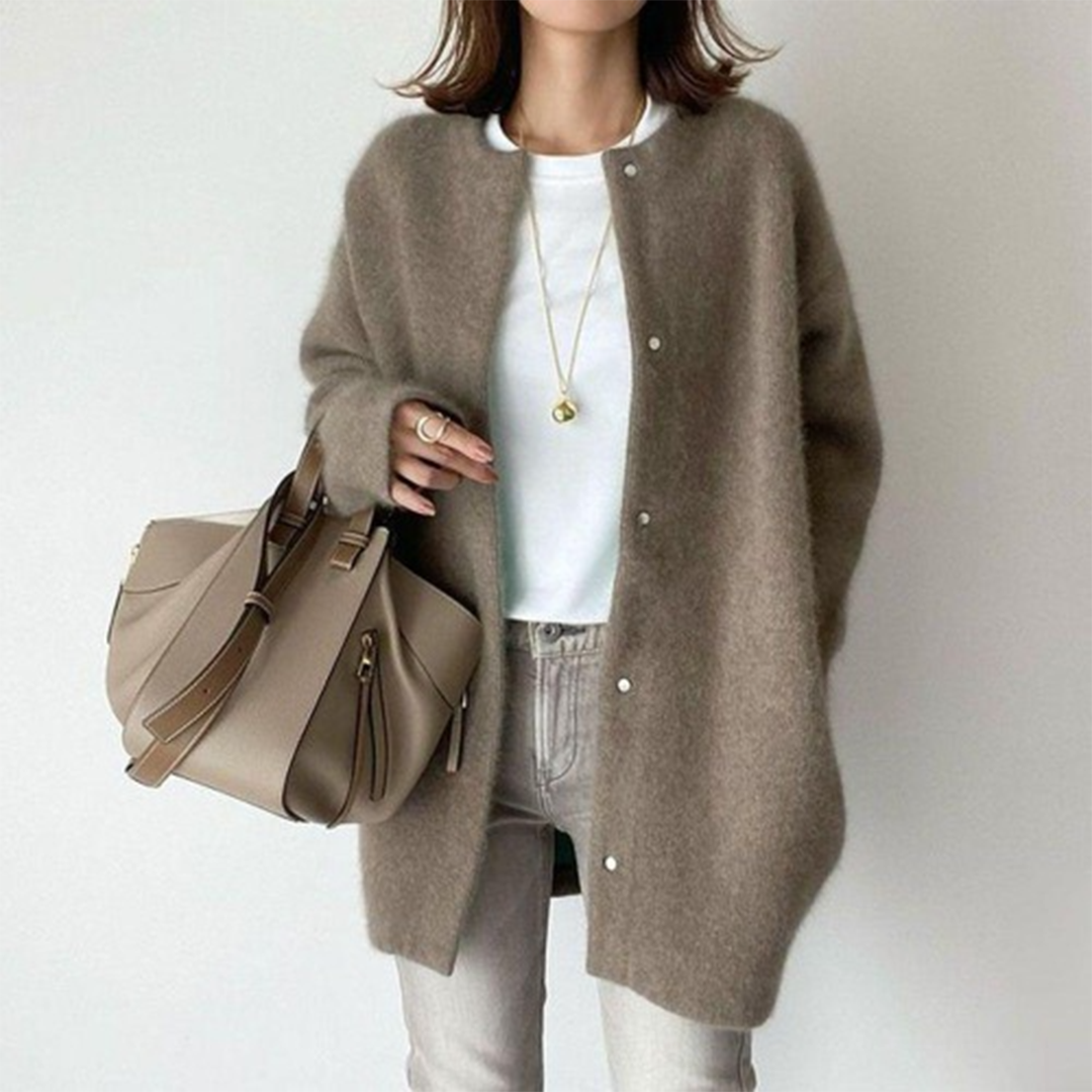 Woman wearing a minimalist longline button cardigan over a top, creating an elegant, casual look.