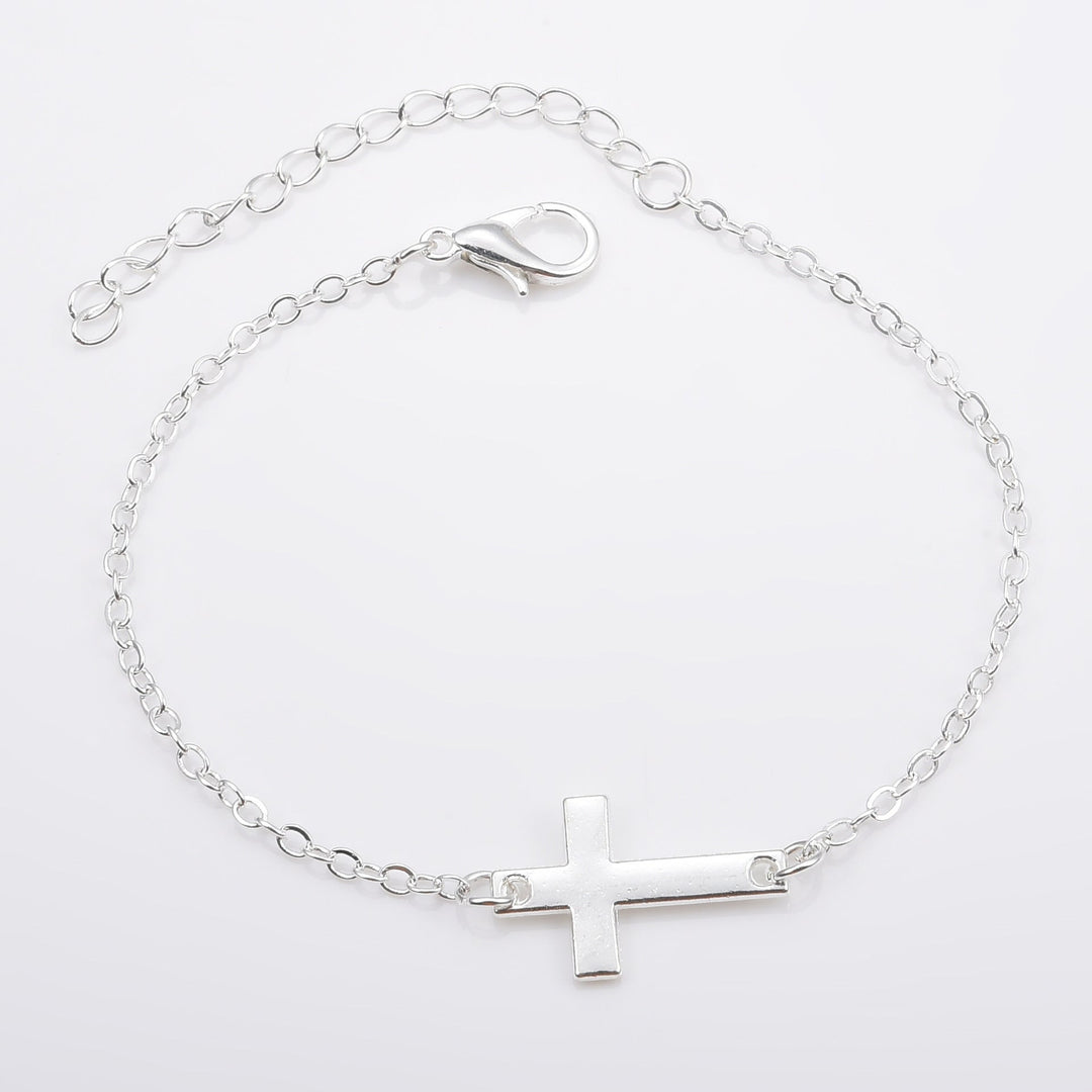 Close-up of minimalist silver cross charm on a delicate women's bracelet, spiritual and elegant.
