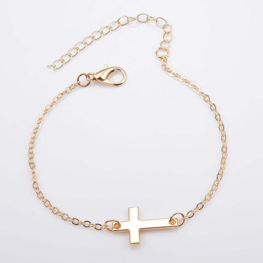 Minimalist silver cross bracelet worn on a woman's wrist, adjustable and elegant faith jewelry.