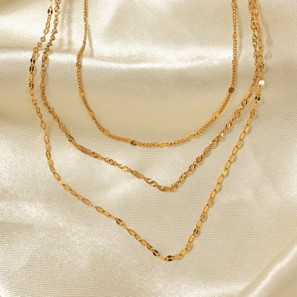 Close-up of women's gold-toned multi-layer necklace featuring assorted chains and lustrous pearls.