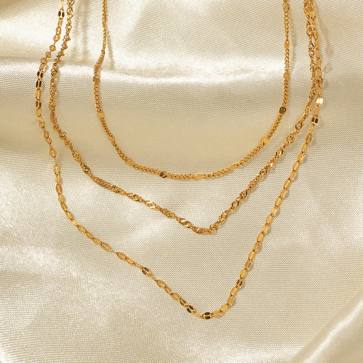 Close-up of women's gold-toned multi-layer necklace featuring assorted chains and lustrous pearls.