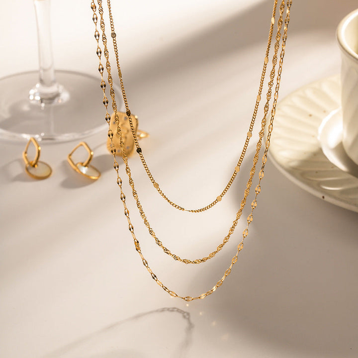 Fashionable multi-layered gold chain necklace with pearls adorning a woman's neck. Versatile jewelry.