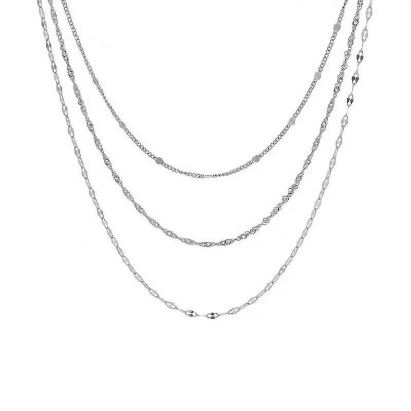 Detailed view of a women's intricate multi-layered gold necklace, combining various chain styles and pearls.