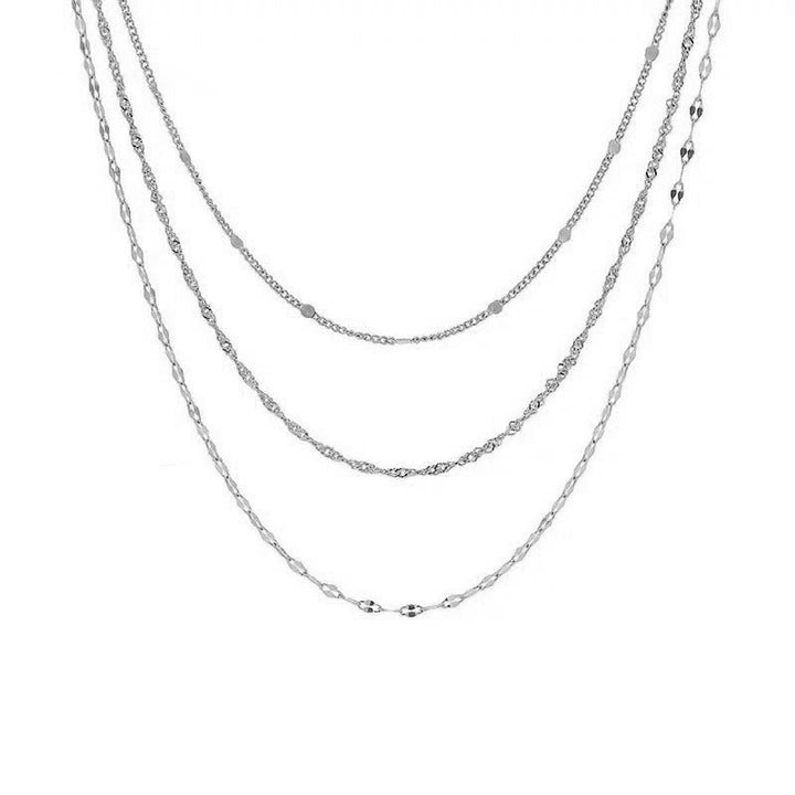 Detailed view of a women's intricate multi-layered gold necklace, combining various chain styles and pearls.
