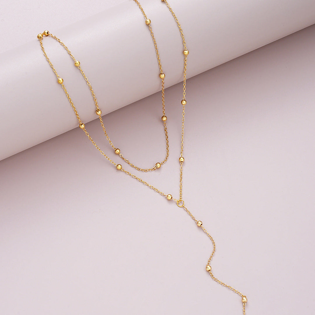 Fashionable women's multi-layered gold lariat charm necklace. Versatile accessory for everyday or special occasions.