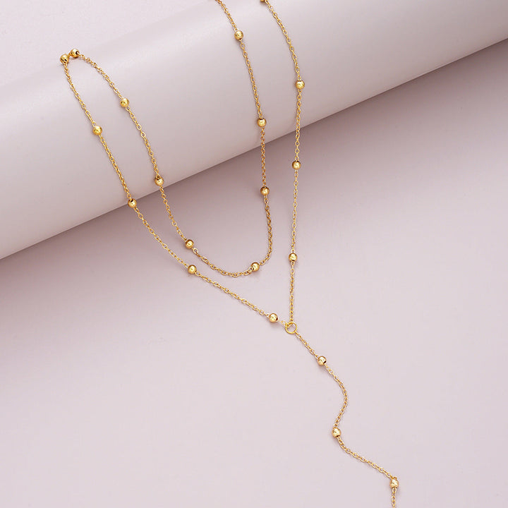 Fashionable women's multi-layered gold lariat charm necklace. Versatile accessory for everyday or special occasions.
