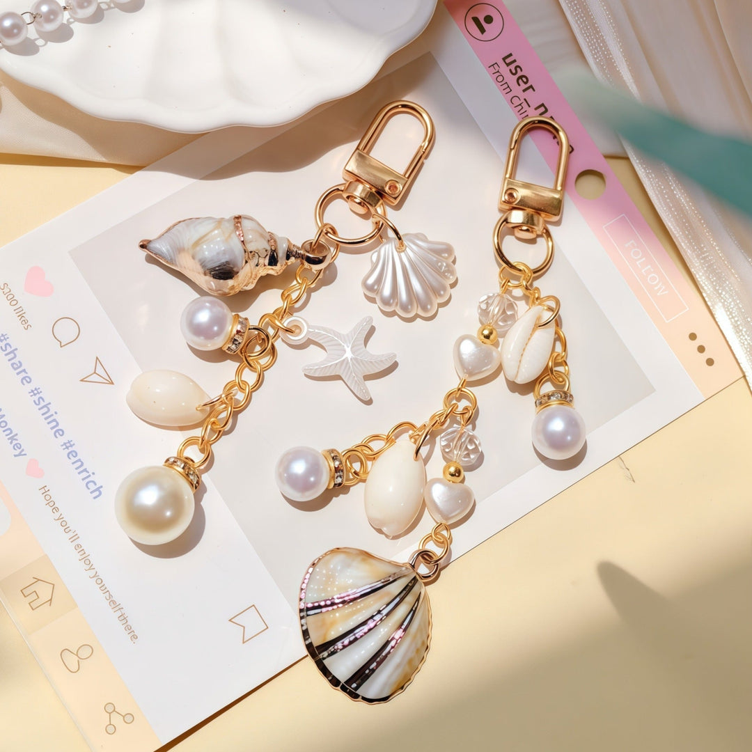 Gold-tone women's keychain featuring a detailed shell, starfish, and faux pearl for a seaside look.