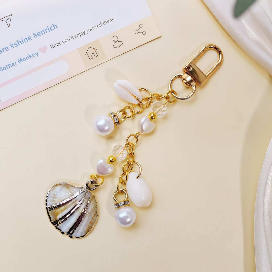 Chic women's maritime keychain with shell, starfish, and pearl charms, perfect ocean-inspired accessory.