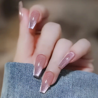 Women's nude pink glittery press-on nails with cat eye effect, perfect for stylish and easy nail art.