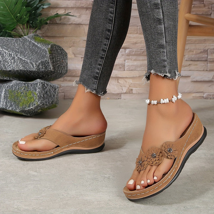 Stylish slip-on women's sandals featuring flower detail, comfortable wedge heel & orthopedic support.