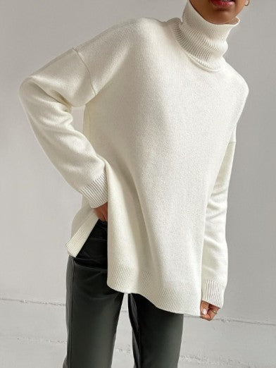 Woman models an oversized turtleneck sweater with side slits, showcasing a cozy & chic winter outfit.