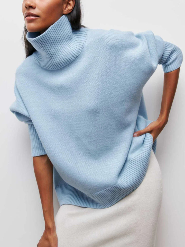 Chic women's oversized turtleneck sweater with unique elbow slits, a cozy knitwear essential for fall.