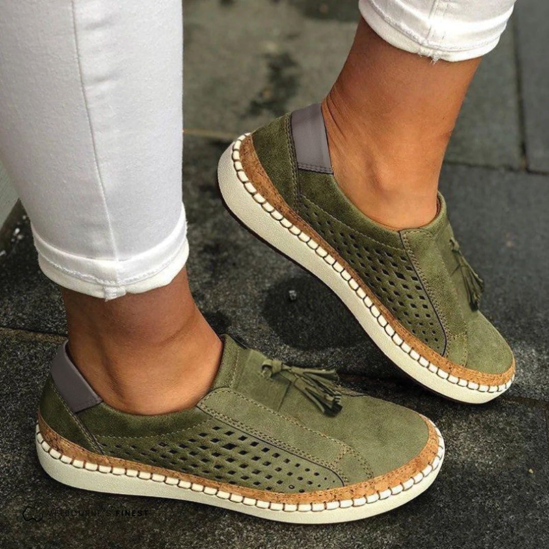 Women's perforated slip-on flats with chic tassels. Comfortable vegan leather footwear for everyday style.