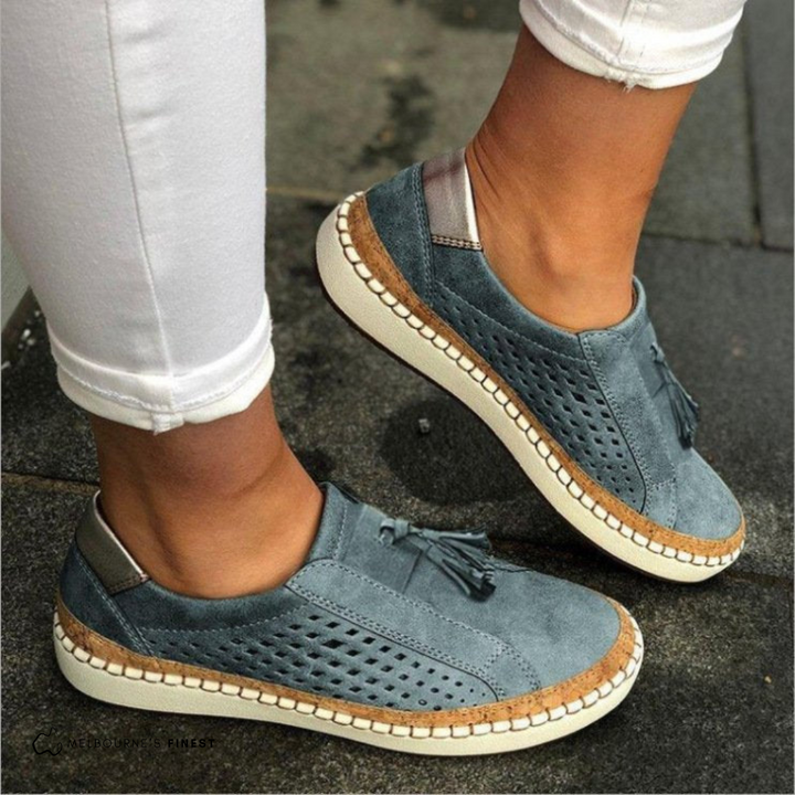 Everyday women's perforated slip-on flats. Fashionable vegan leather footwear with stylish tassel accents.