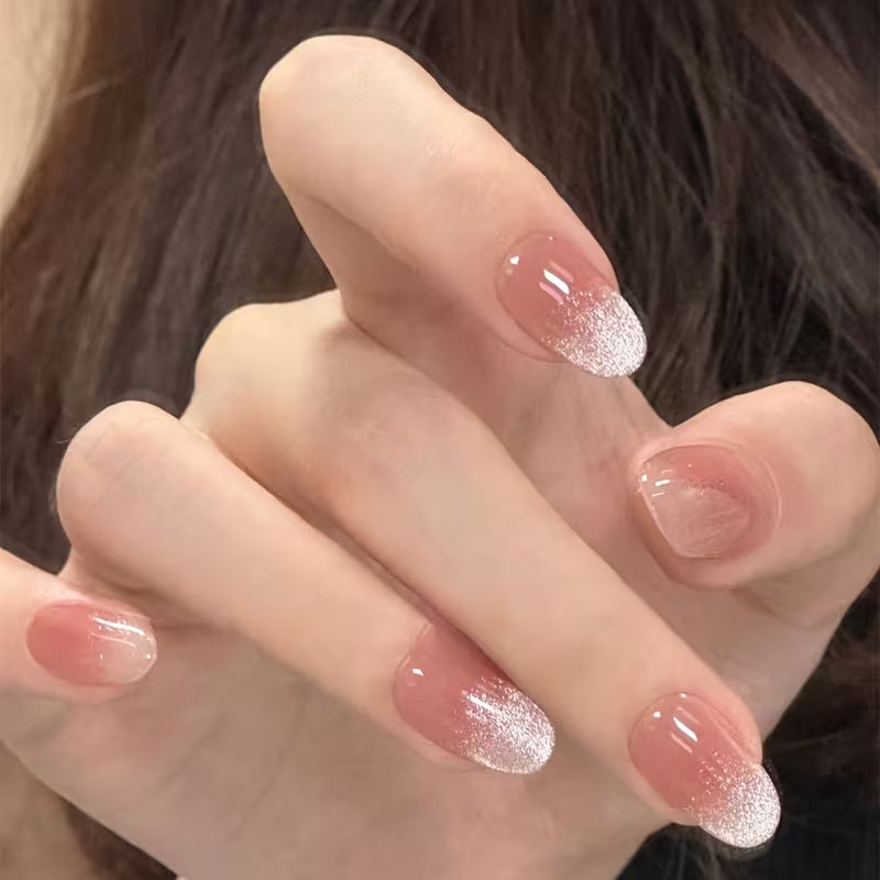 Close-up of pink glitter French tip fake nails, showcasing elegant design and shimmering finish.