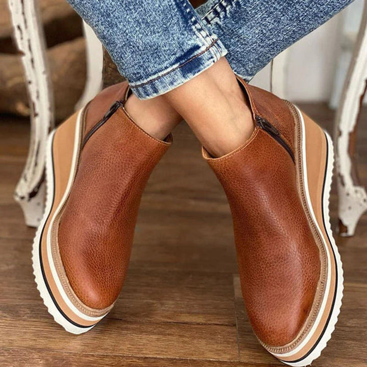 Elevated women's platform wedge ankle boots, showcasing a chunky sole, stable wedge, and convenient side zip.