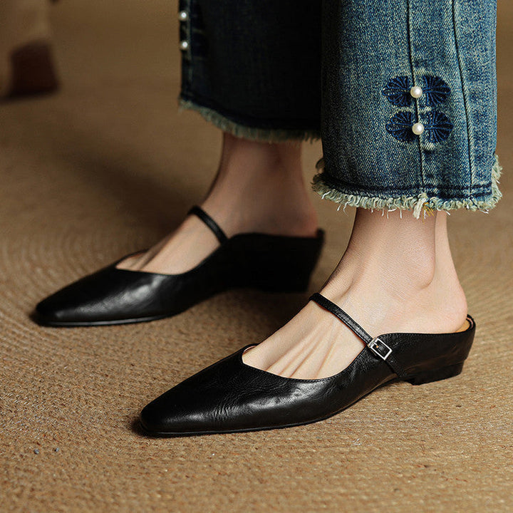 Women's pointed toe mule flats, elegant black, with a refined strap accent.