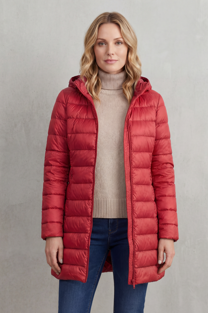 Packable women's hooded puffer jacket shown in travel pouch. Ultra-warm, lightweight outerwear for on-the-go comfort.