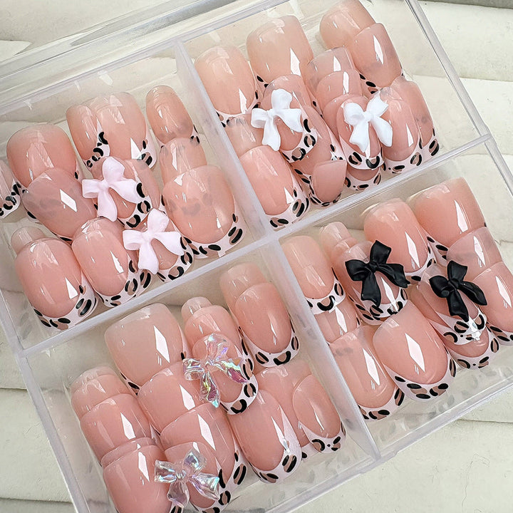 Fashionable fake nails with delicate bow accents, offering a quick and stylish nail art manicure.