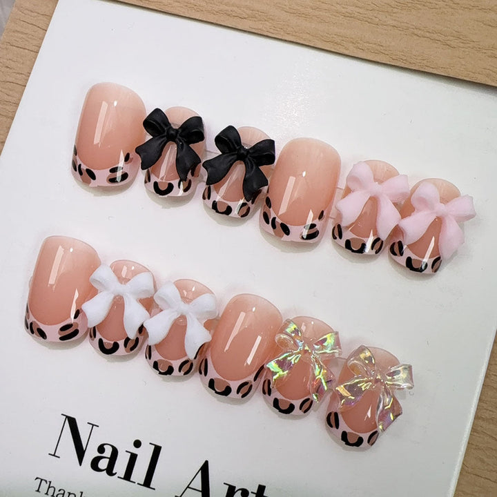 Glamorous women's press-on nails with cute bow accents, perfect for a chic and easy manicure at home.