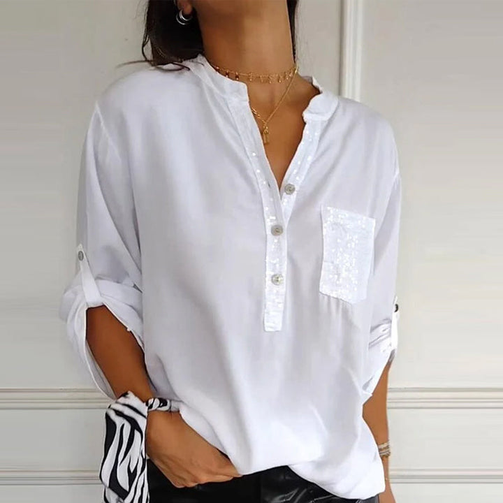 Close-up of sequin trim on an elegant women's button-up blouse, showcasing sparkle and detail.