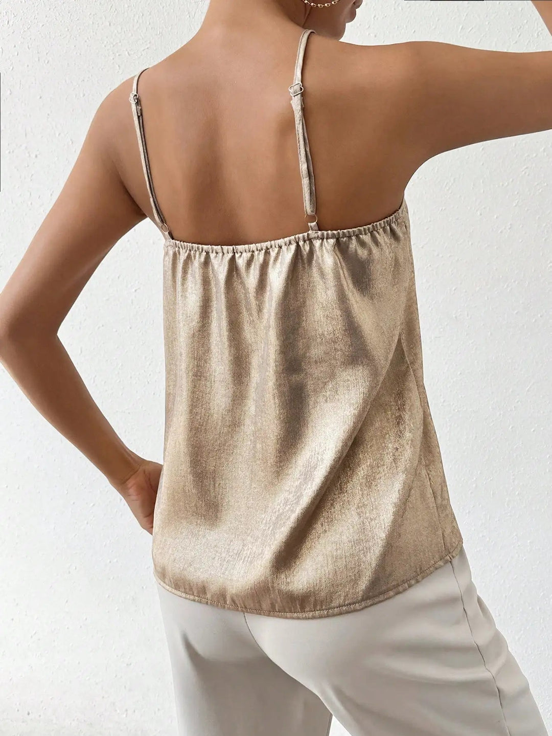 Elegant women's metallic V-neck cami top with adjustable straps, styled for a glamorous party outfit.