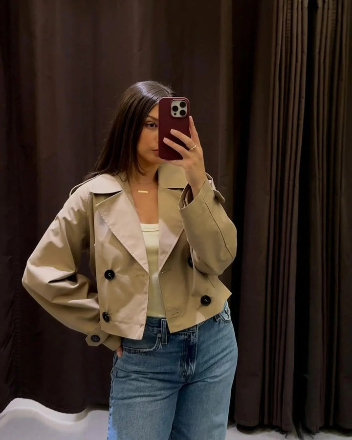 Close-up: Double-breasted short trench coat with buttons. Khaki women's transitional jacket, elegant classic style.