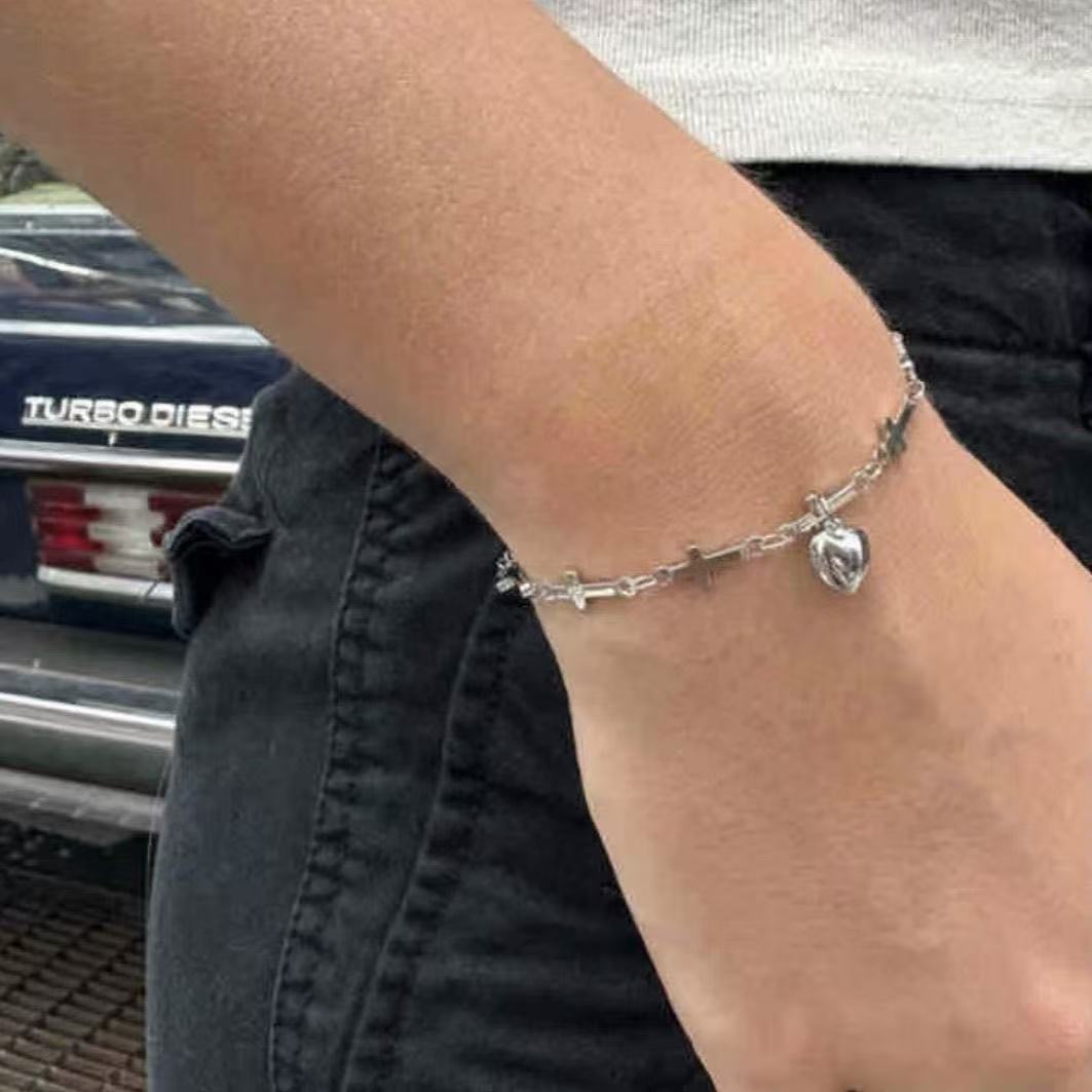 Elegant women's charm bracelet featuring symbolic cross and heart charms, a thoughtful gift for her, adjustable design.