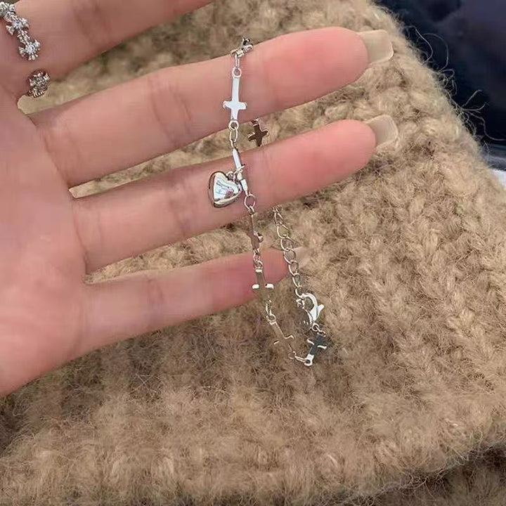 Stylish women's adjustable bracelet with polished silver-tone cross and heart charms, perfect for everyday fashion.