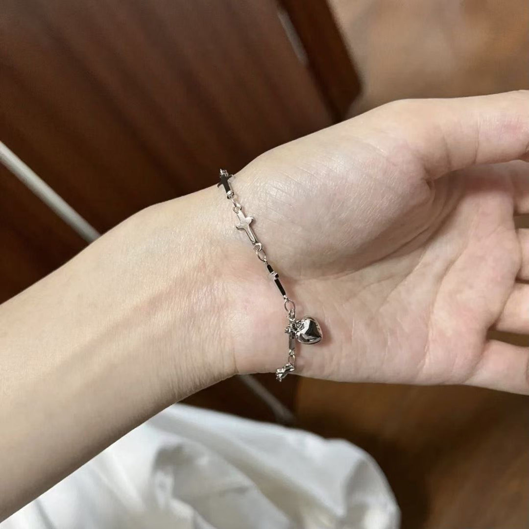 Delicate women's adjustable charm bracelet showcasing intertwined cross and heart pendants, a unique symbolic accessory.