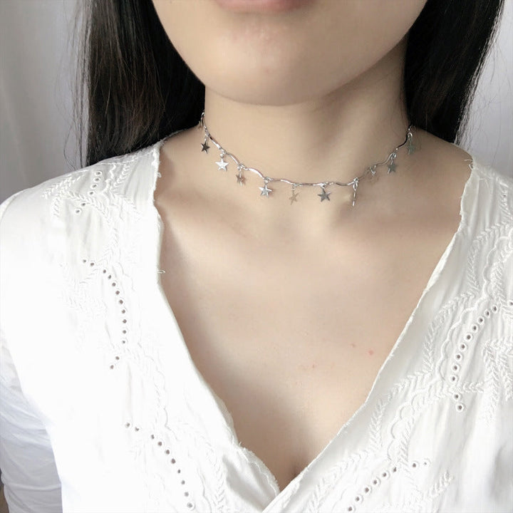 Close-up of a silver tone linked chain necklace featuring intricate celestial star charms for women.